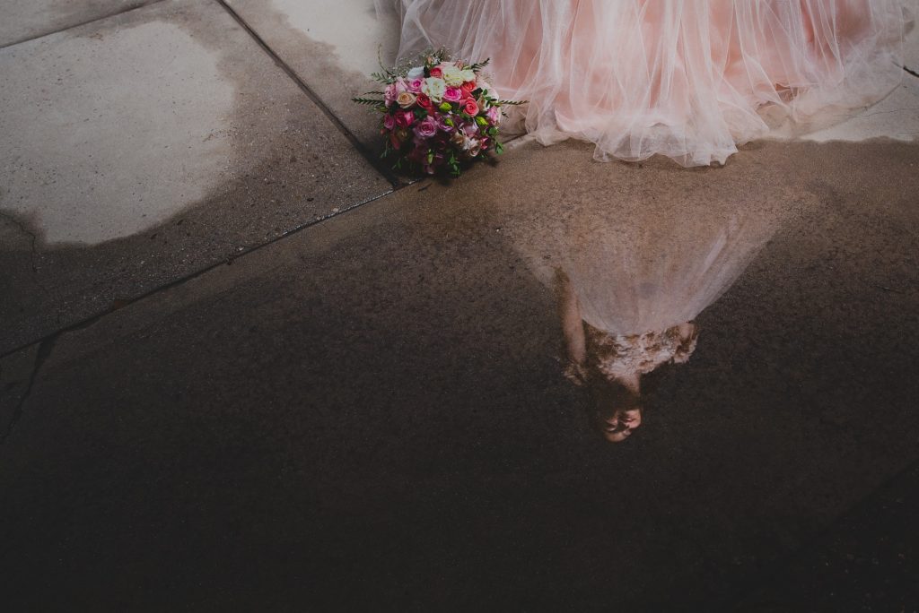 Reflejo de quinceañera junto a su ramo en charco de lluvia en la Universidad de Sonora de Hermosillo. 